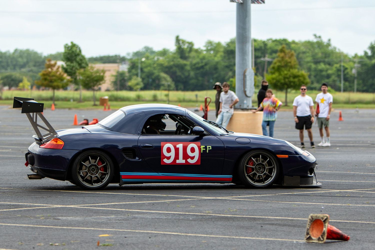 Porsche 919 FP race car competing in an autocross event on a parking lot course marked with orange cones.