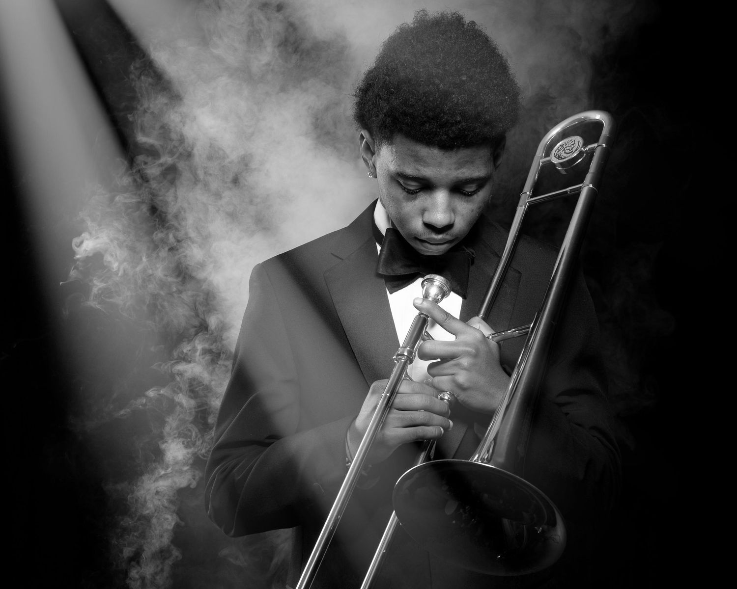 A high school senior musician plays trombone in dramatic black and white lighting with smoke effects in a series of artistic shots.