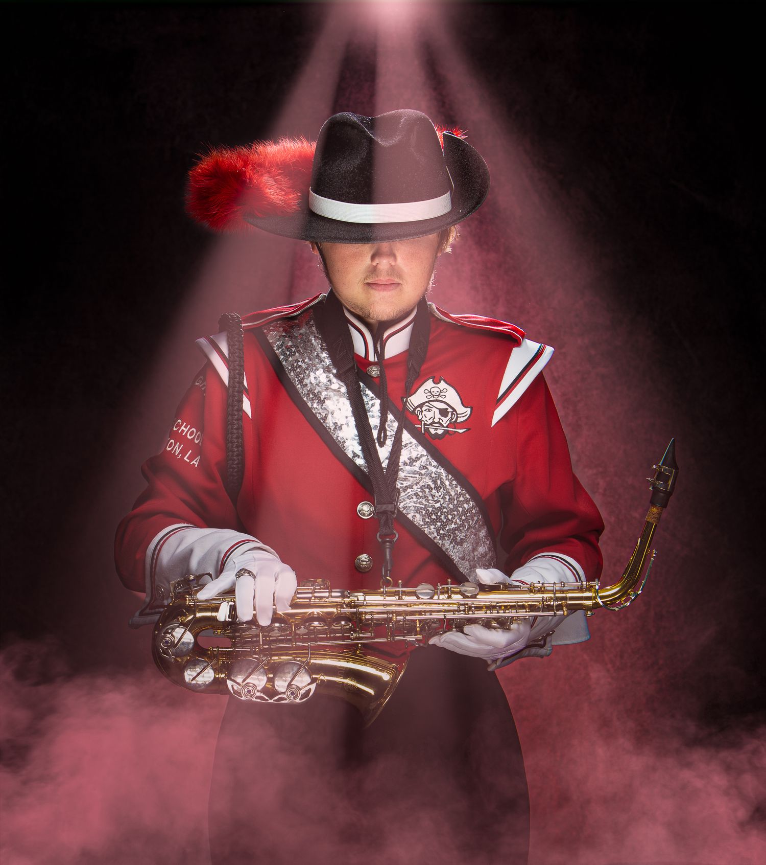 Louisiana's Haughton High School Musician in red marching band uniform holds saxophone while posing in dramatic lighting with smoke effects.