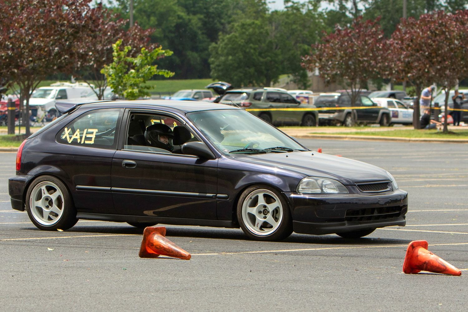 Dark blue Honda Civic hatchback navigating an autocross course marked with orange cones in a parking lot.
