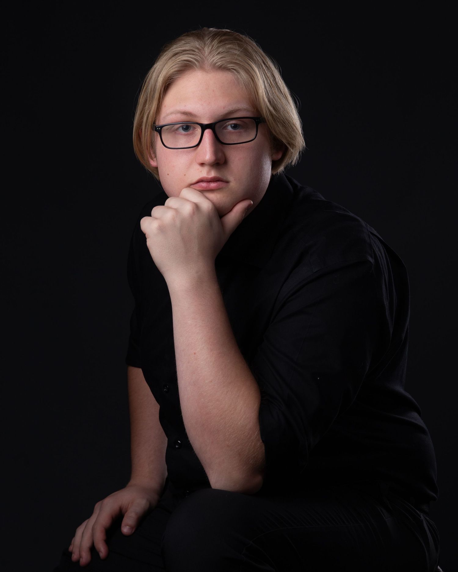 A dramatic black and white portrait series showing contemplative poses against a dark background.