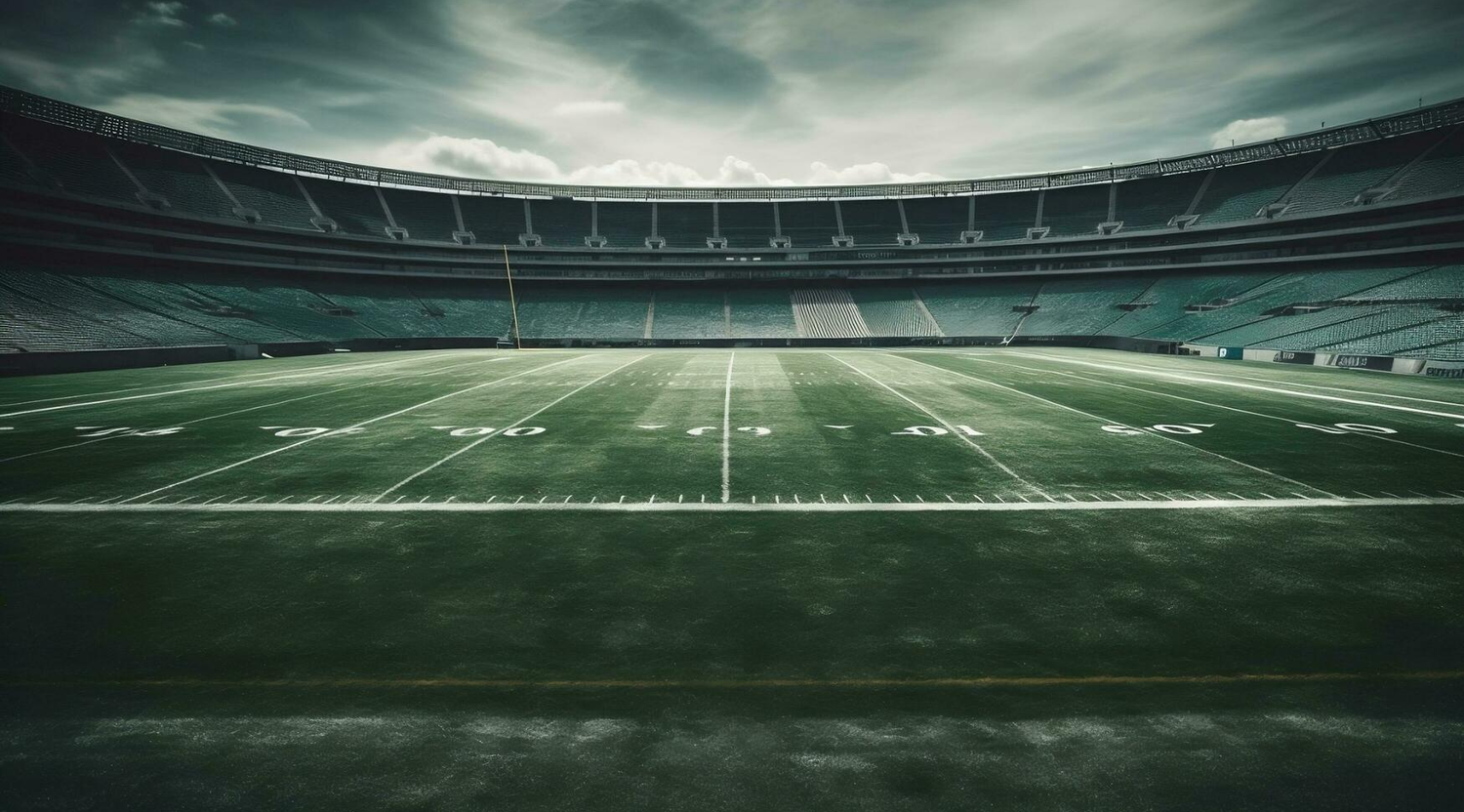 Empty NFL football stadium with green turf field, yard lines, and dramatic cloudy sky overhead.