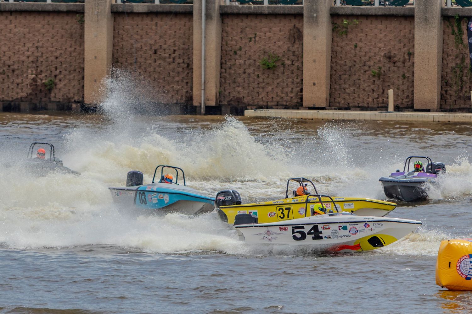 Three colorful speedboats race across choppy water, spraying white foam during an exciting powerboat racing competition.