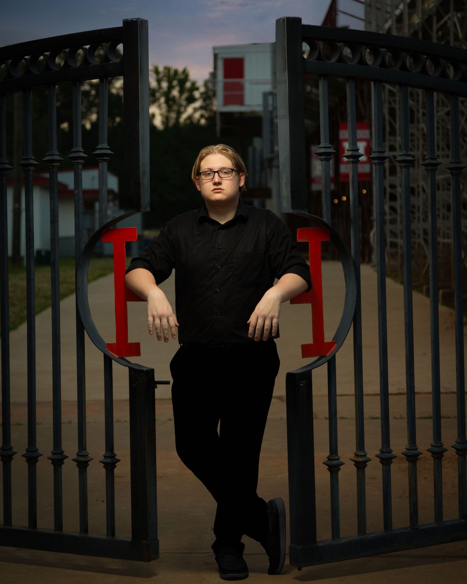 A series of dramatic sunset portraits showing a person in black clothing posed against ornate metal gates and fencing.