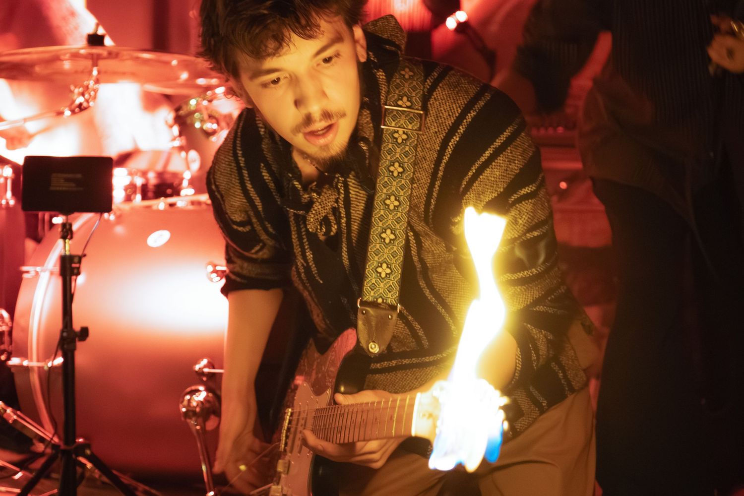 Musicians perform on stage bathed in dramatic red and yellow lighting effects.