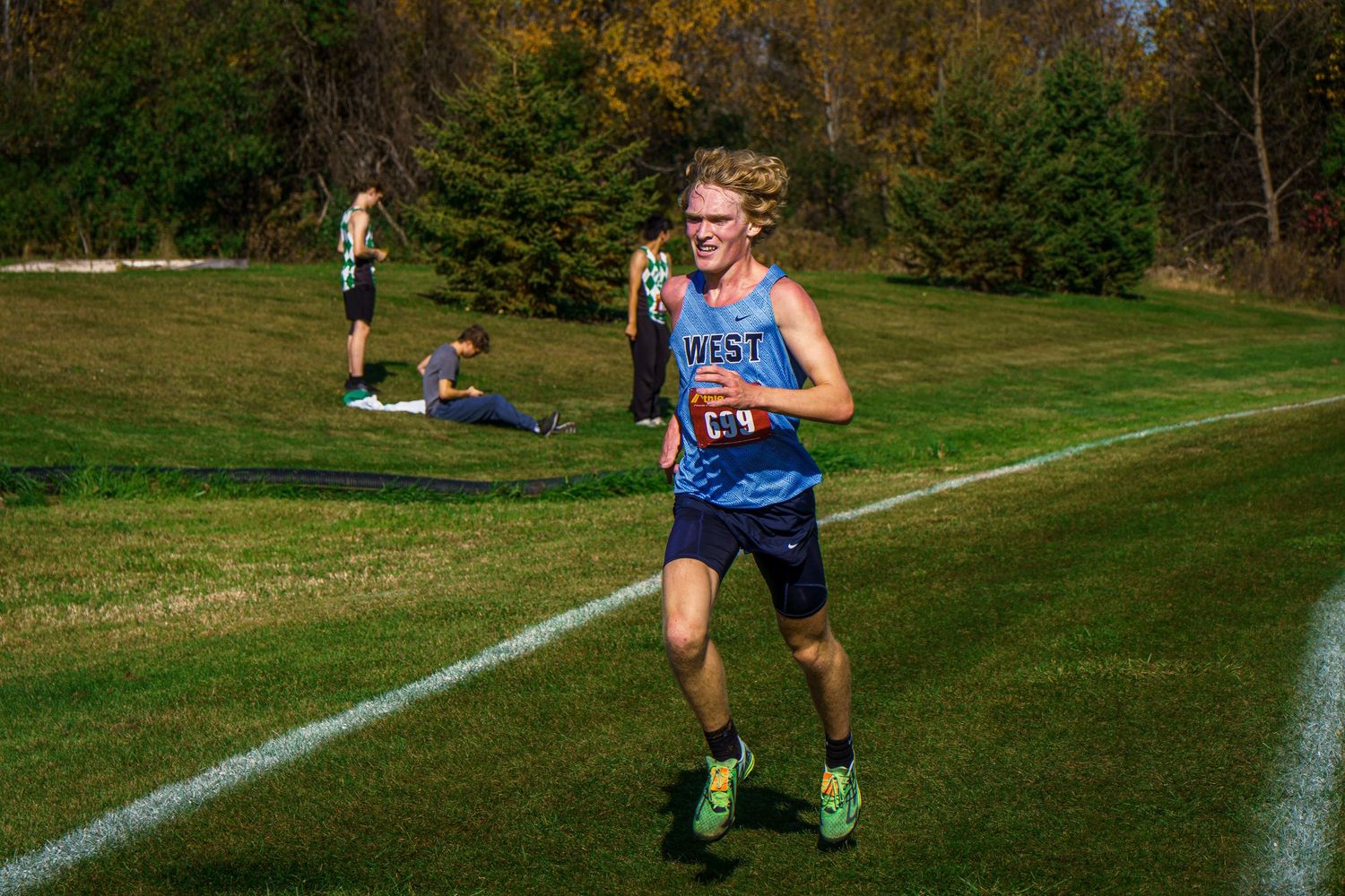 Cross country runners sprinting on a marked grass course during a competitive race.