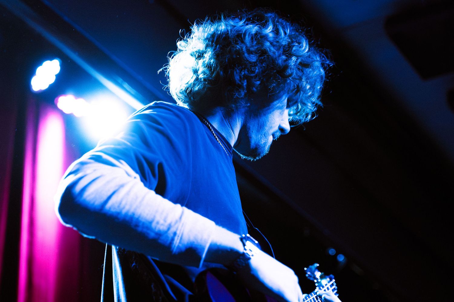 Silhouetted figure performs on stage with dramatic blue lighting creating an atmospheric concert environment.
