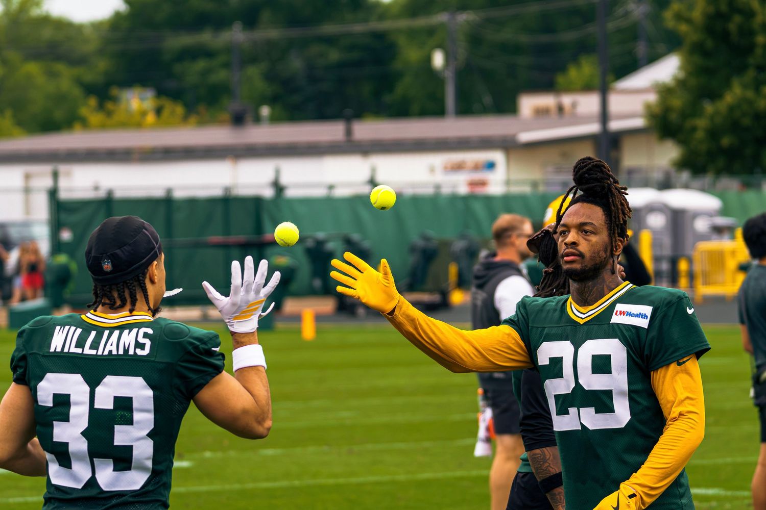 Green Bay Packers players #33 Williams and #29 practice catching drills with tennis balls at training camp.