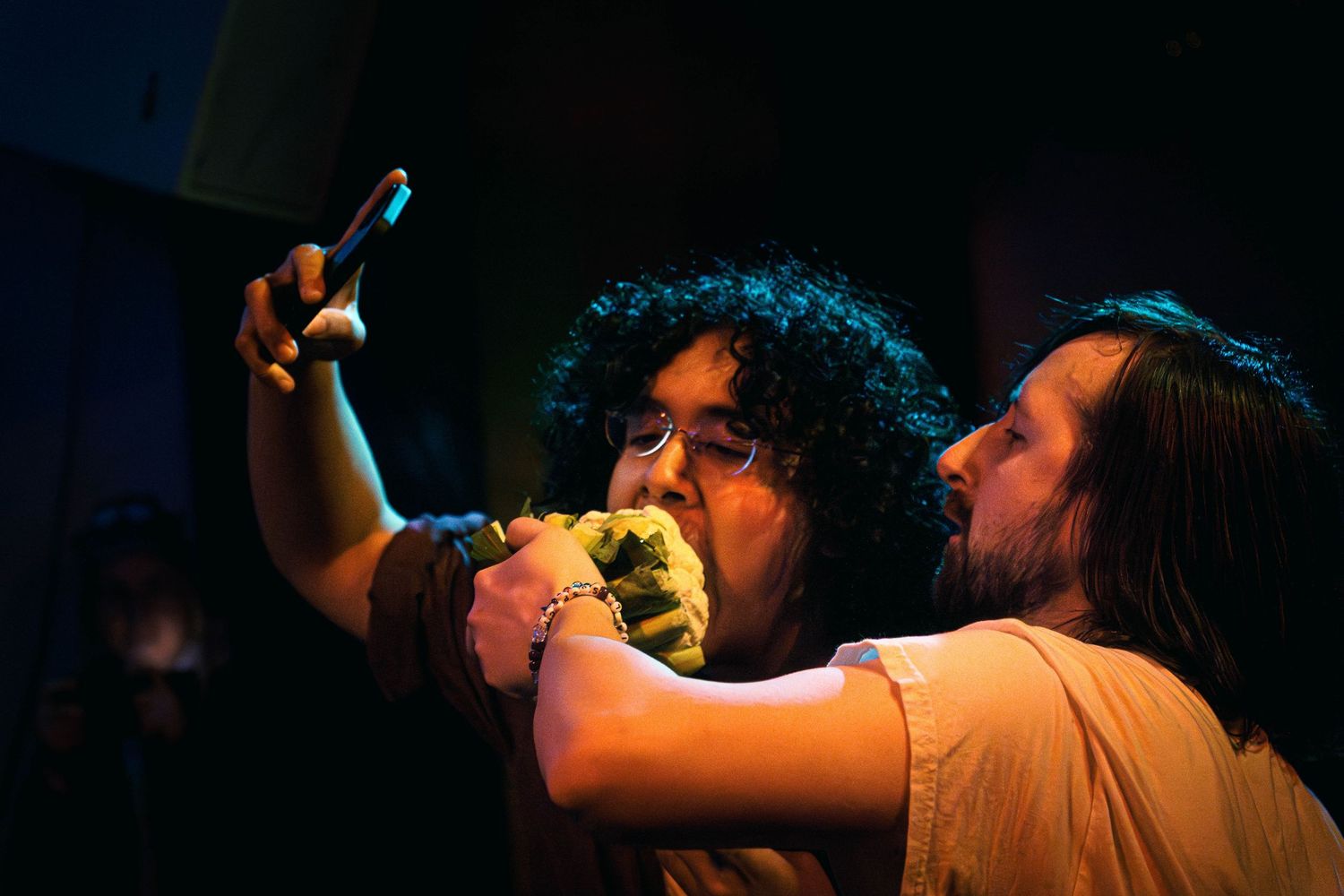 Concert performers on stage in dramatic lighting during an energetic live music performance.