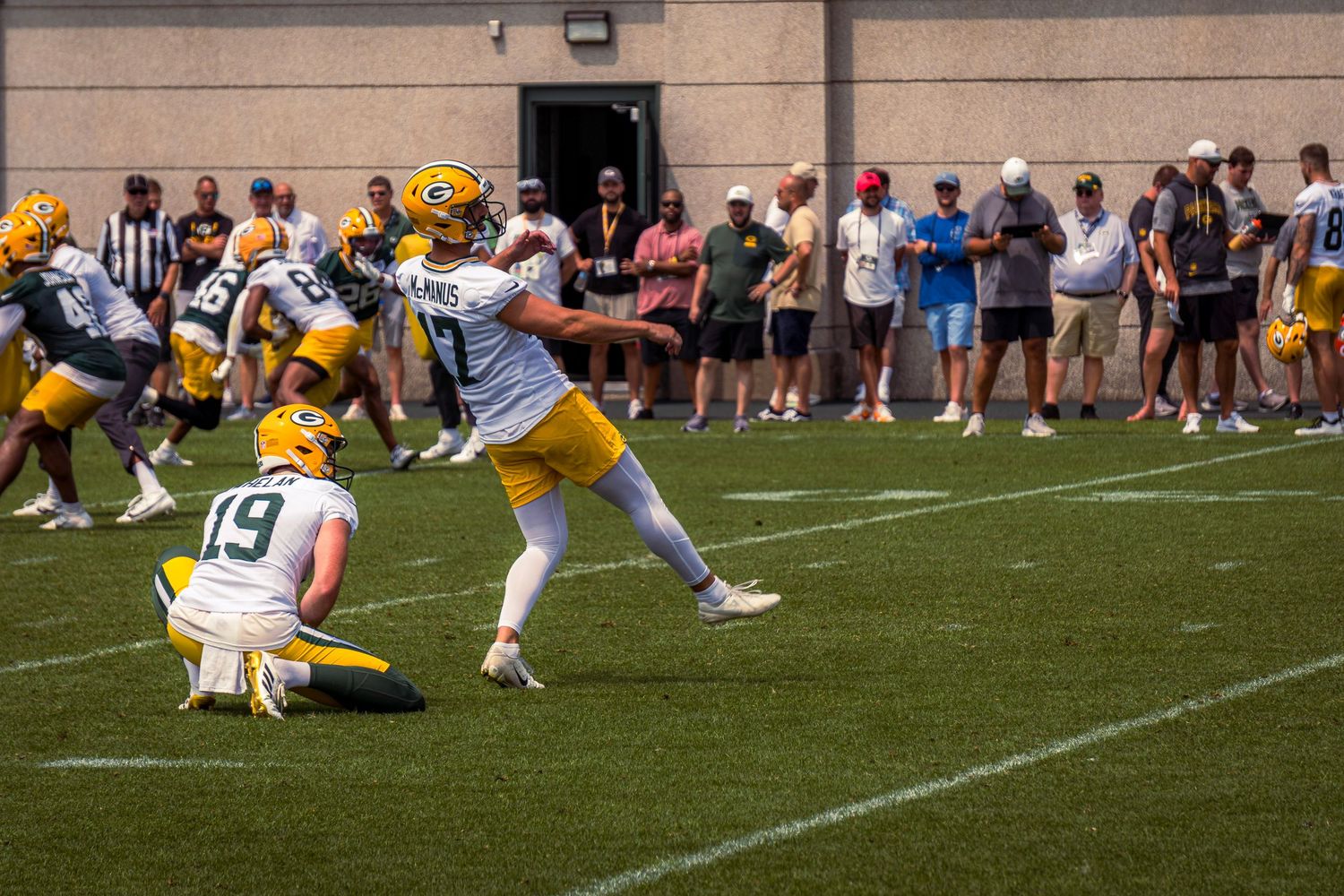 Football players engage in a play on the field during a game with spectators watching from the sidelines.