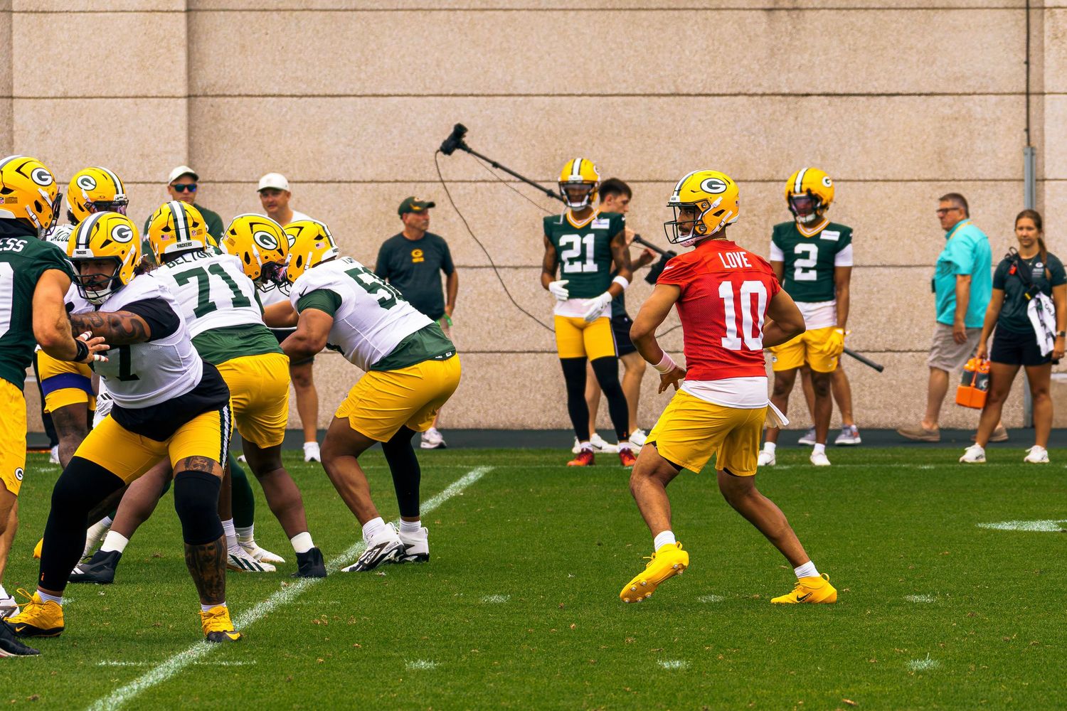 Green Bay Packers quarterback #10 drops back to pass during NFL training camp practice on green turf field.