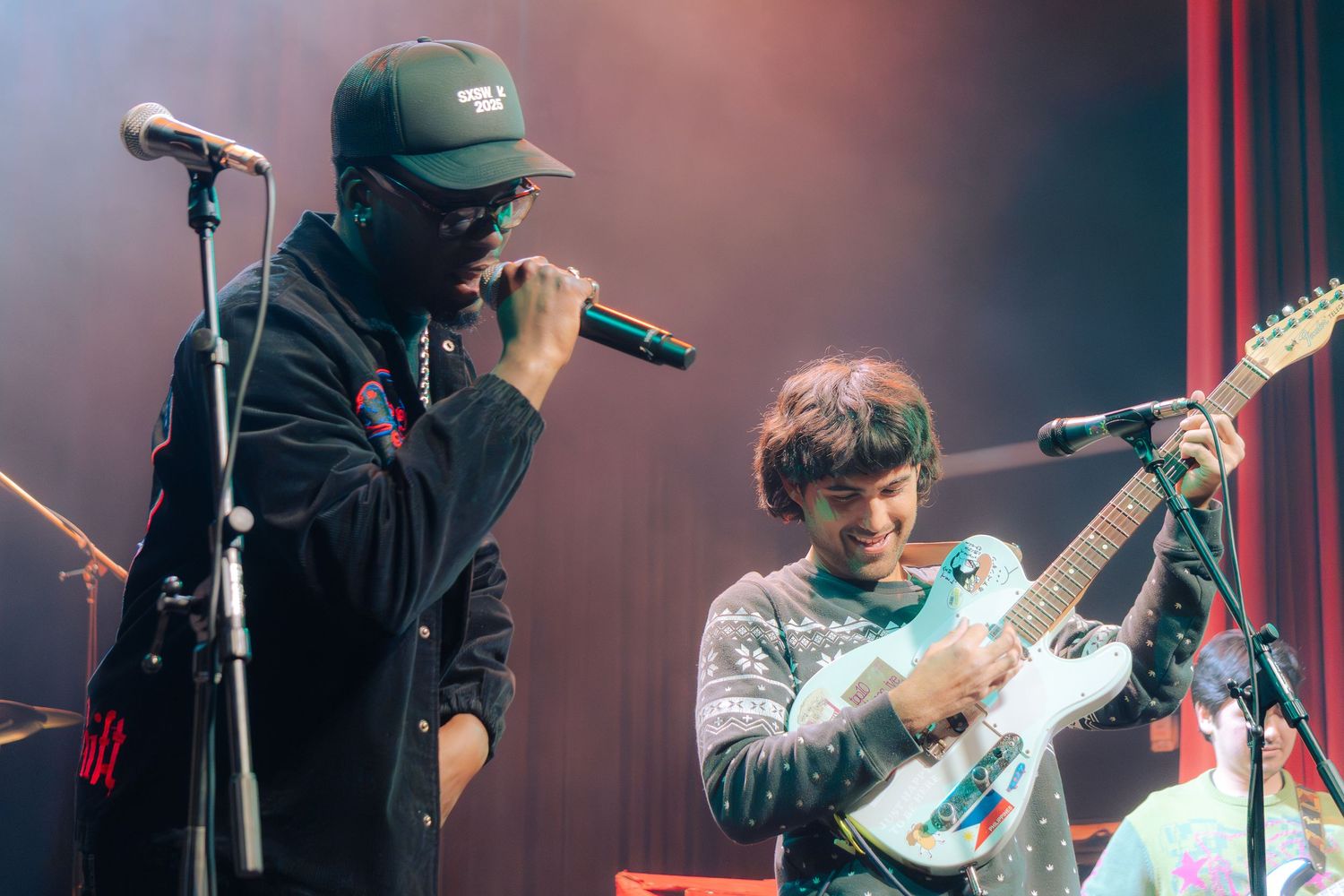 Musicians perform on stage with microphones and instruments during a live concert performance.