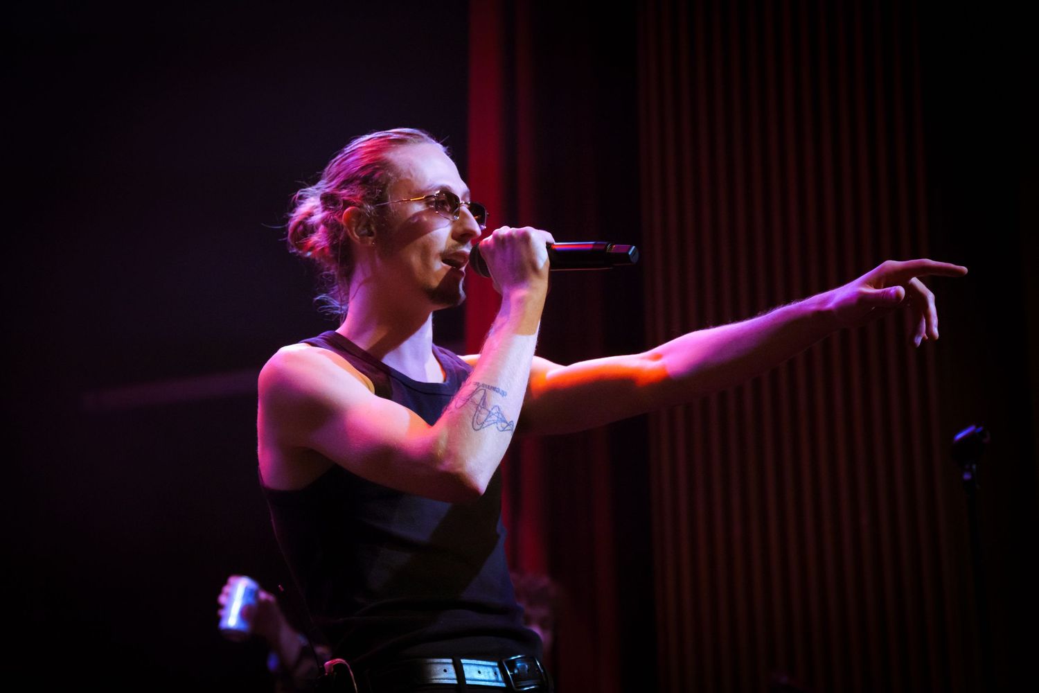 Singer performs passionately on stage under dramatic red and blue lighting during a concert performance.