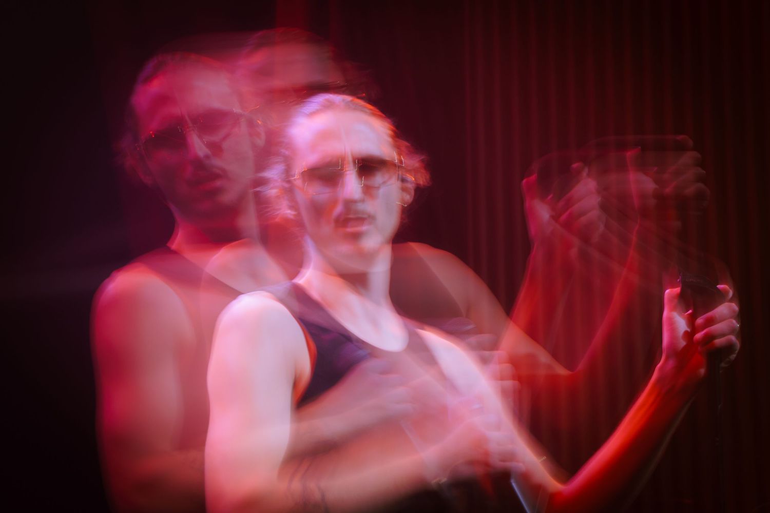 Long exposure photograph showing motion blur with red lighting creates an ethereal double exposure effect.