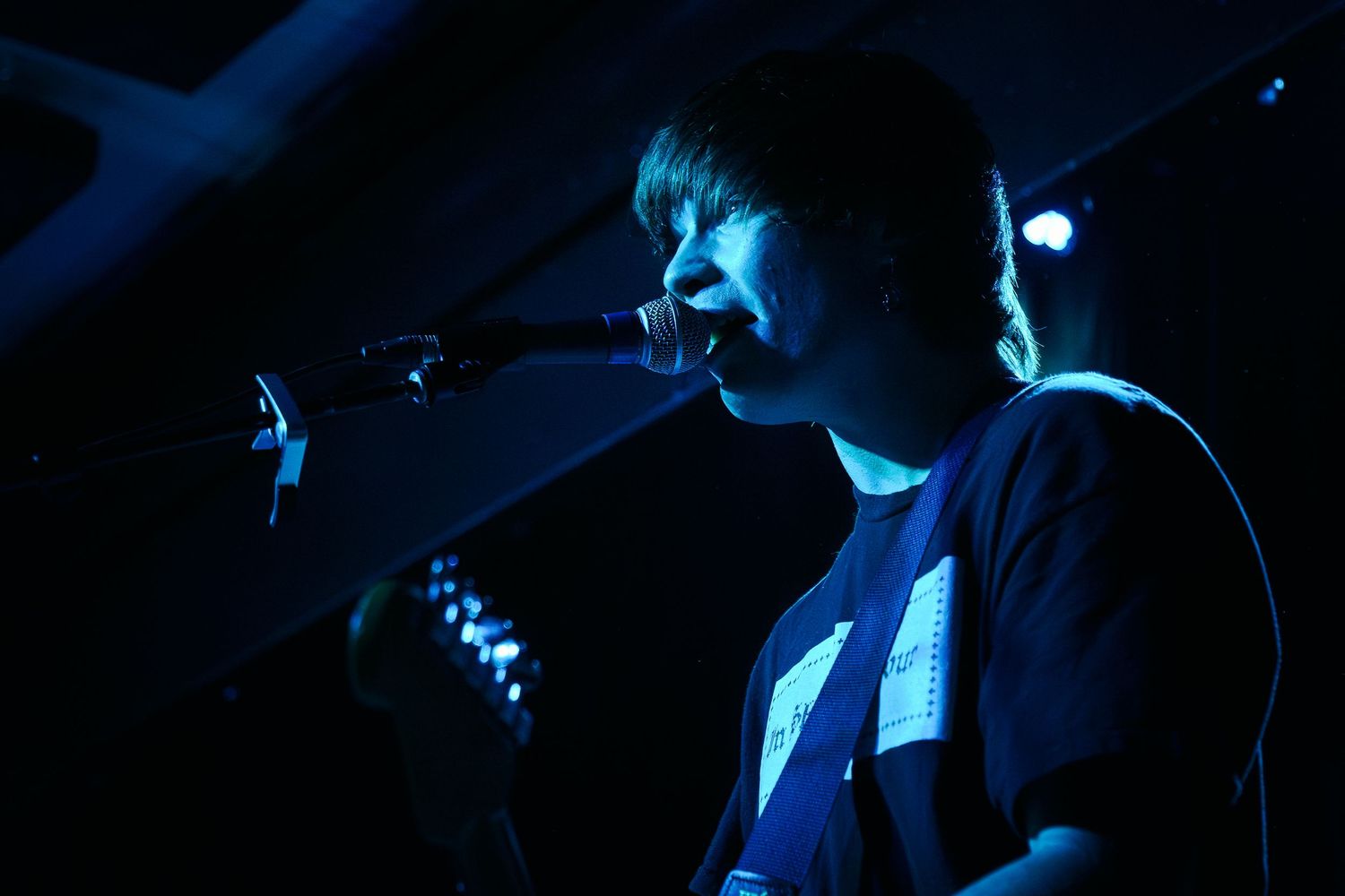 Silhouetted performer on stage illuminated by dramatic blue lighting during a live music performance.