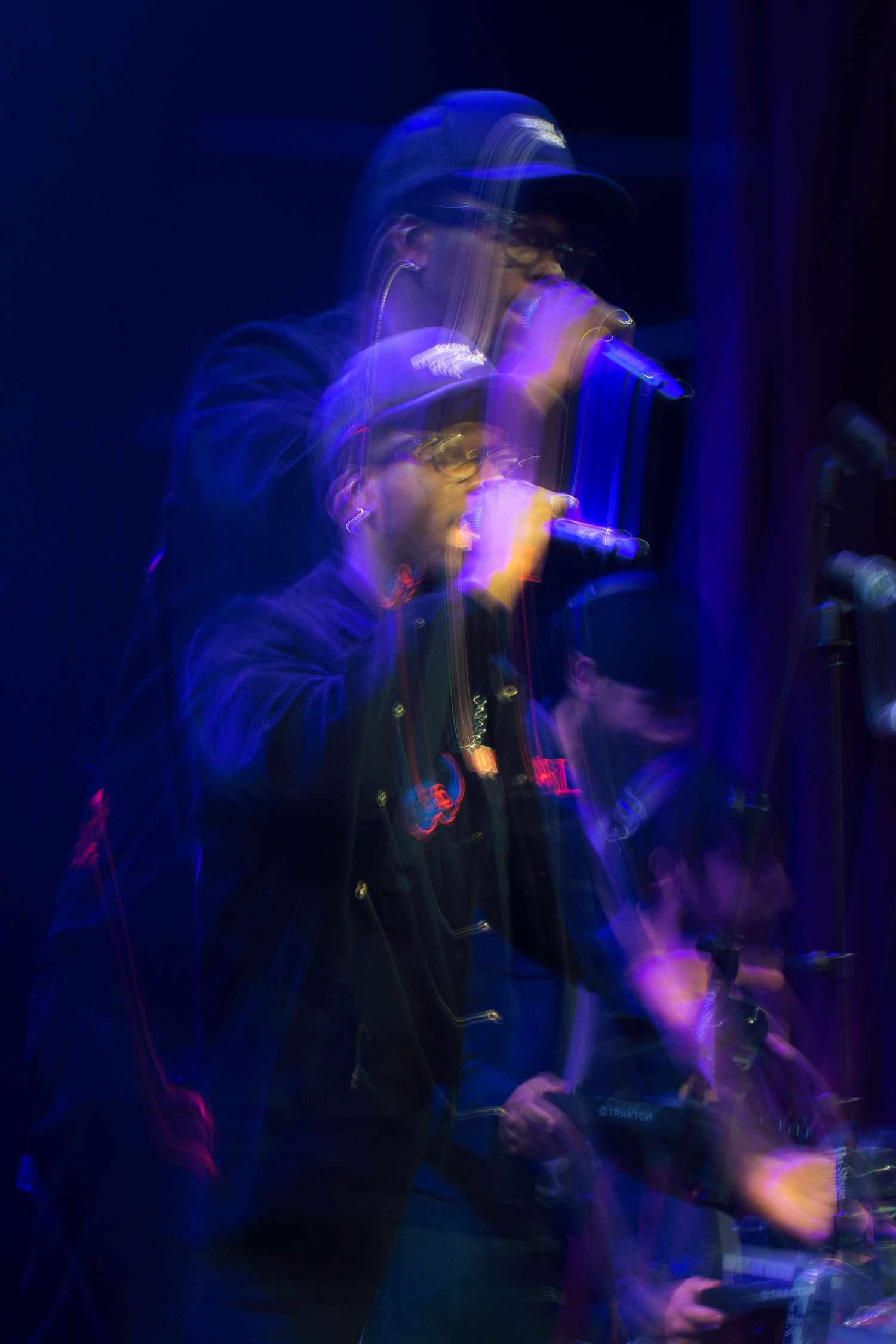 Motion blur captures energetic performance in dark blue stage lighting creating ethereal effect.