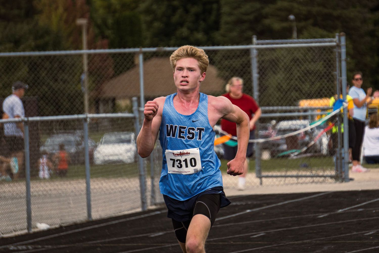 Athletes compete in a track and field event, sprinting down lanes on an outdoor running track.