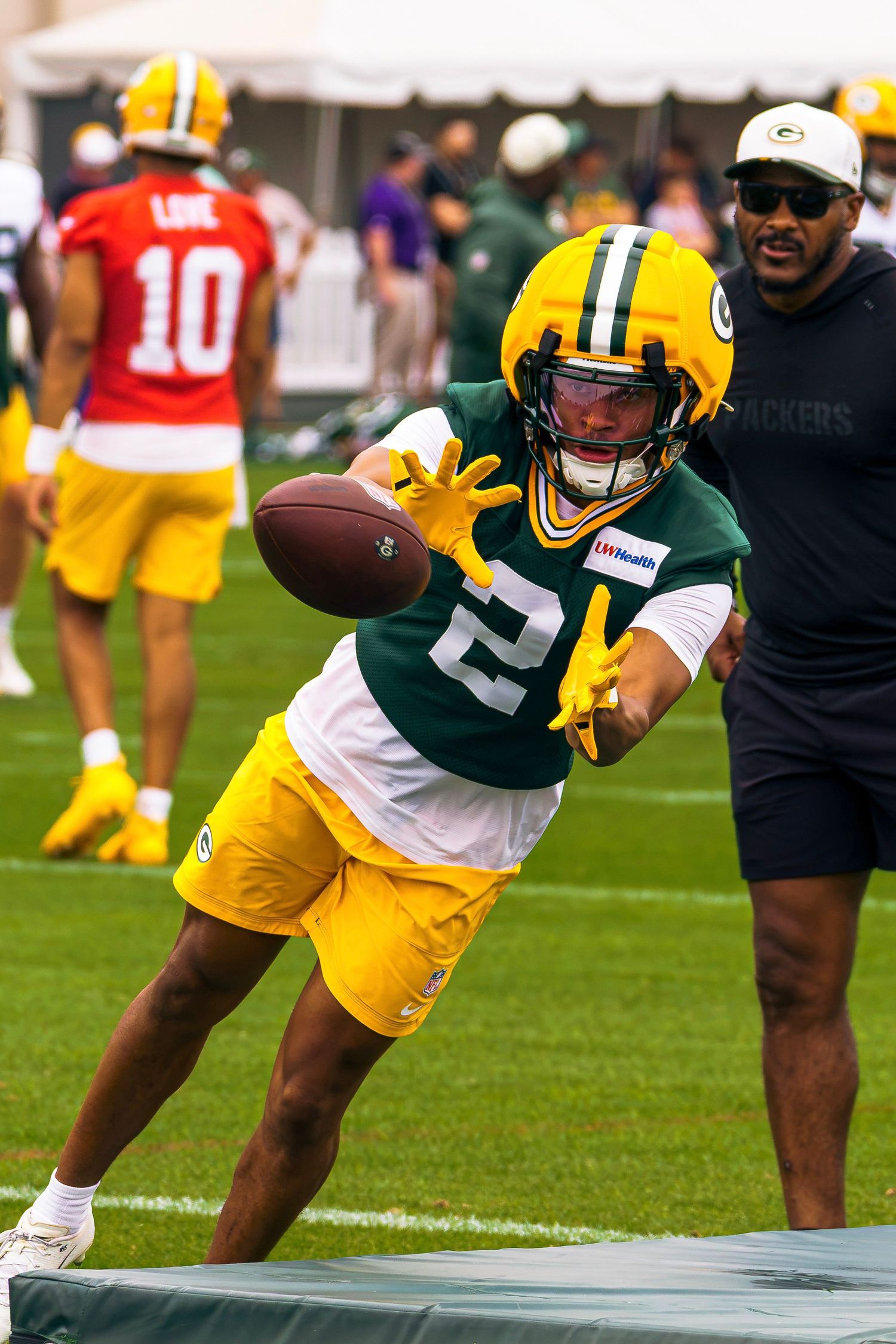 Green Bay Packers player #2 catches a football during training camp practice in green and gold uniform.