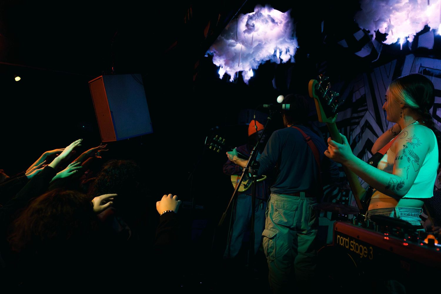 Silhouetted crowd dancing at a nightclub with colorful blue and purple lighting effects in the background.