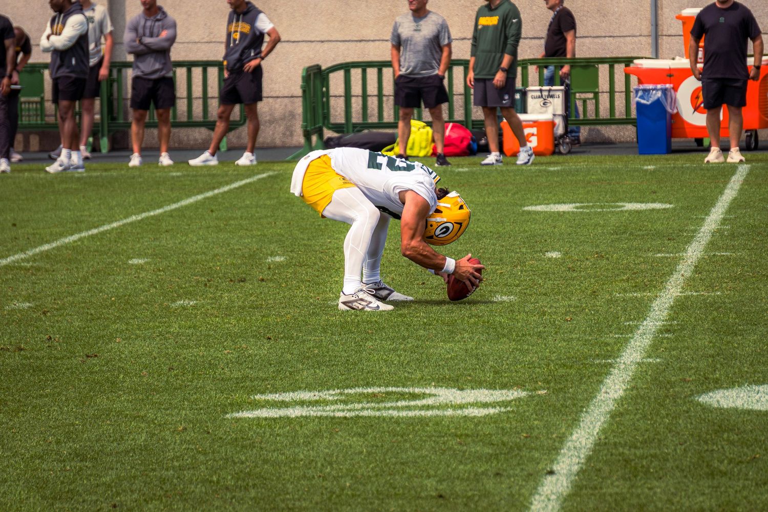 Football players engage in a play on a grass field during a sunny afternoon game.