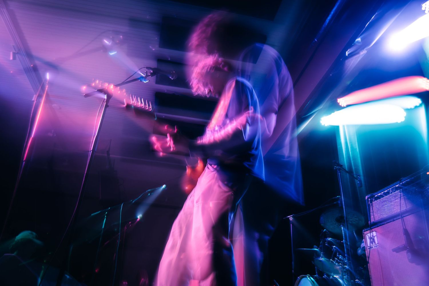 People dancing in a nightclub with vibrant purple and blue lighting creating an energetic party atmosphere.