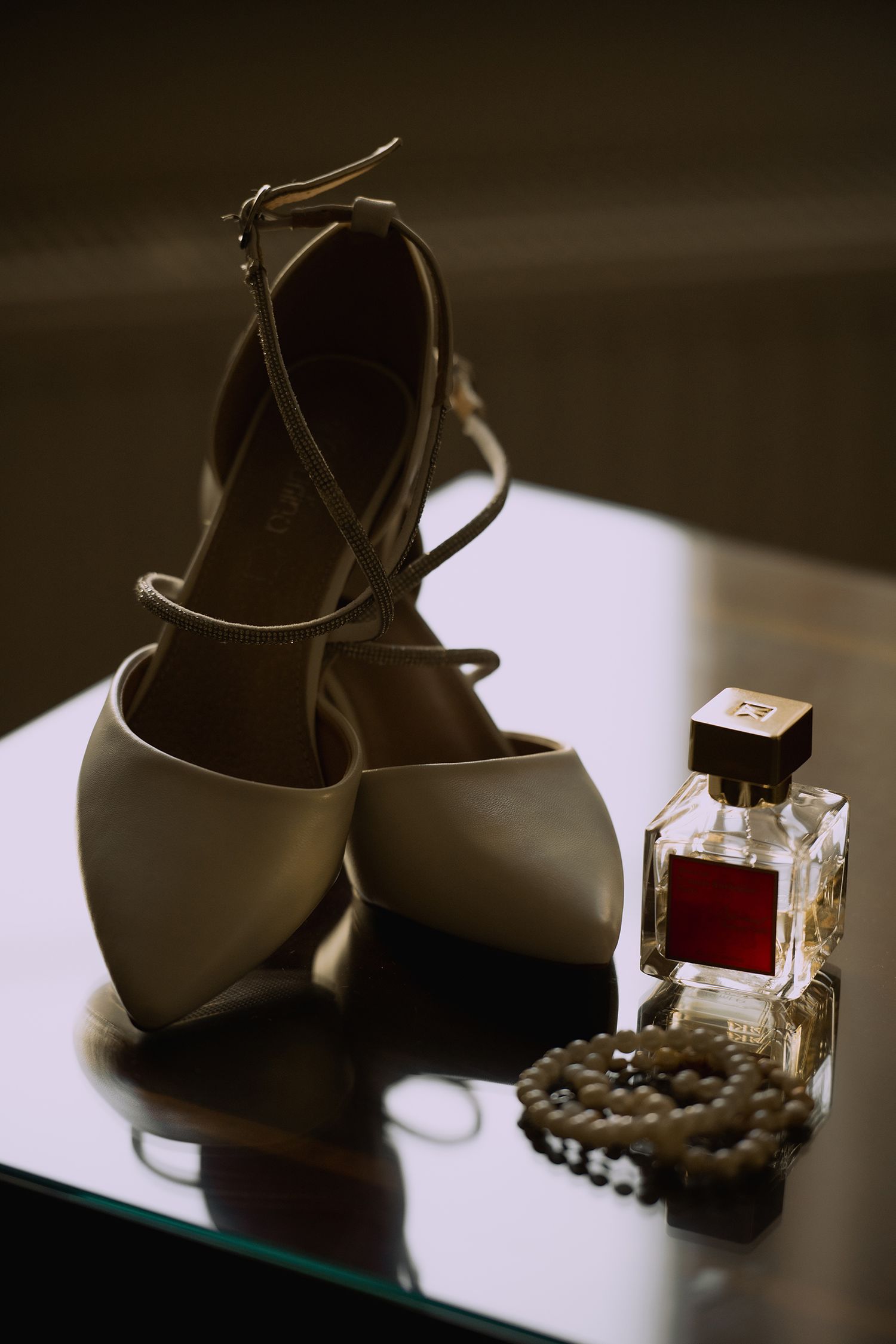 A series of artistic still life photos showing a high heel shoe and perfume bottle against a dark background.