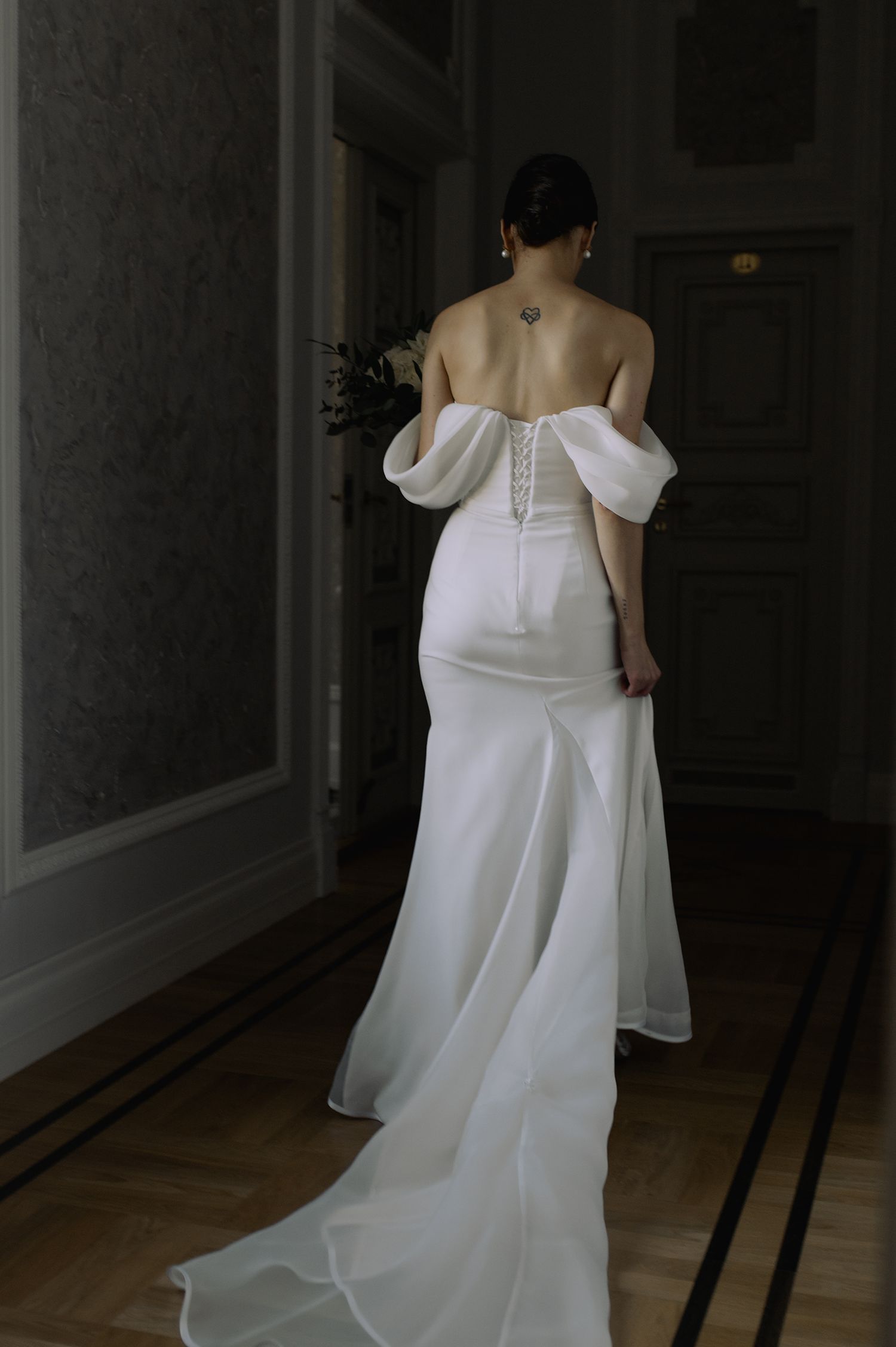 A series of photos showing the back details and movement of a white off-shoulder wedding dress in a dark room.