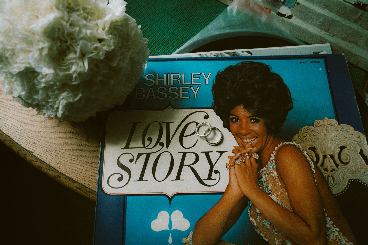 Shirley Bassey Love Story vinyl record album displayed at a vintage market stall with decorative flowers nearby.
