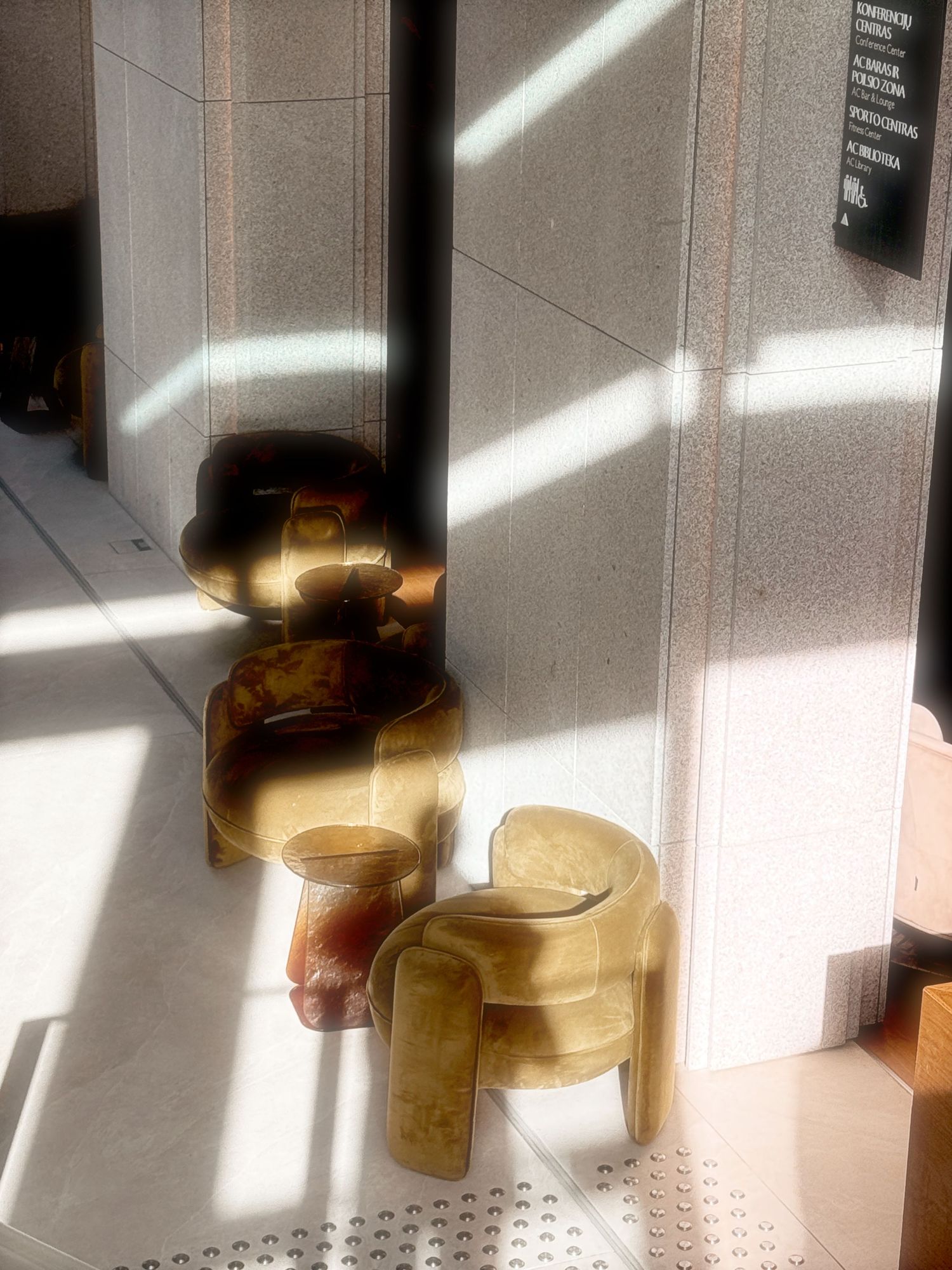Amber-colored acrylic chairs cast dramatic shadows in sunlight streaming through windows onto a light-colored floor.