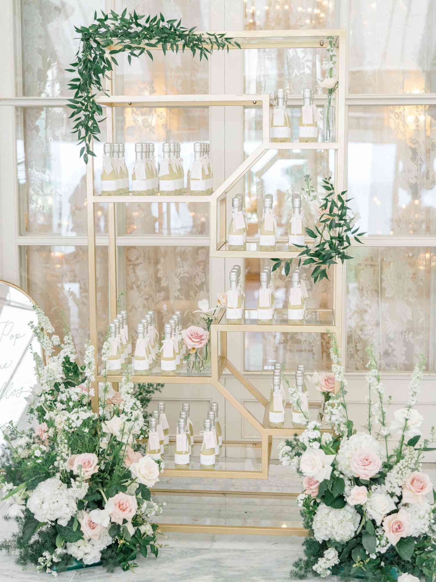 Elegant wedding decor with white and pink floral arrangements and greenery adorning glass display cases.