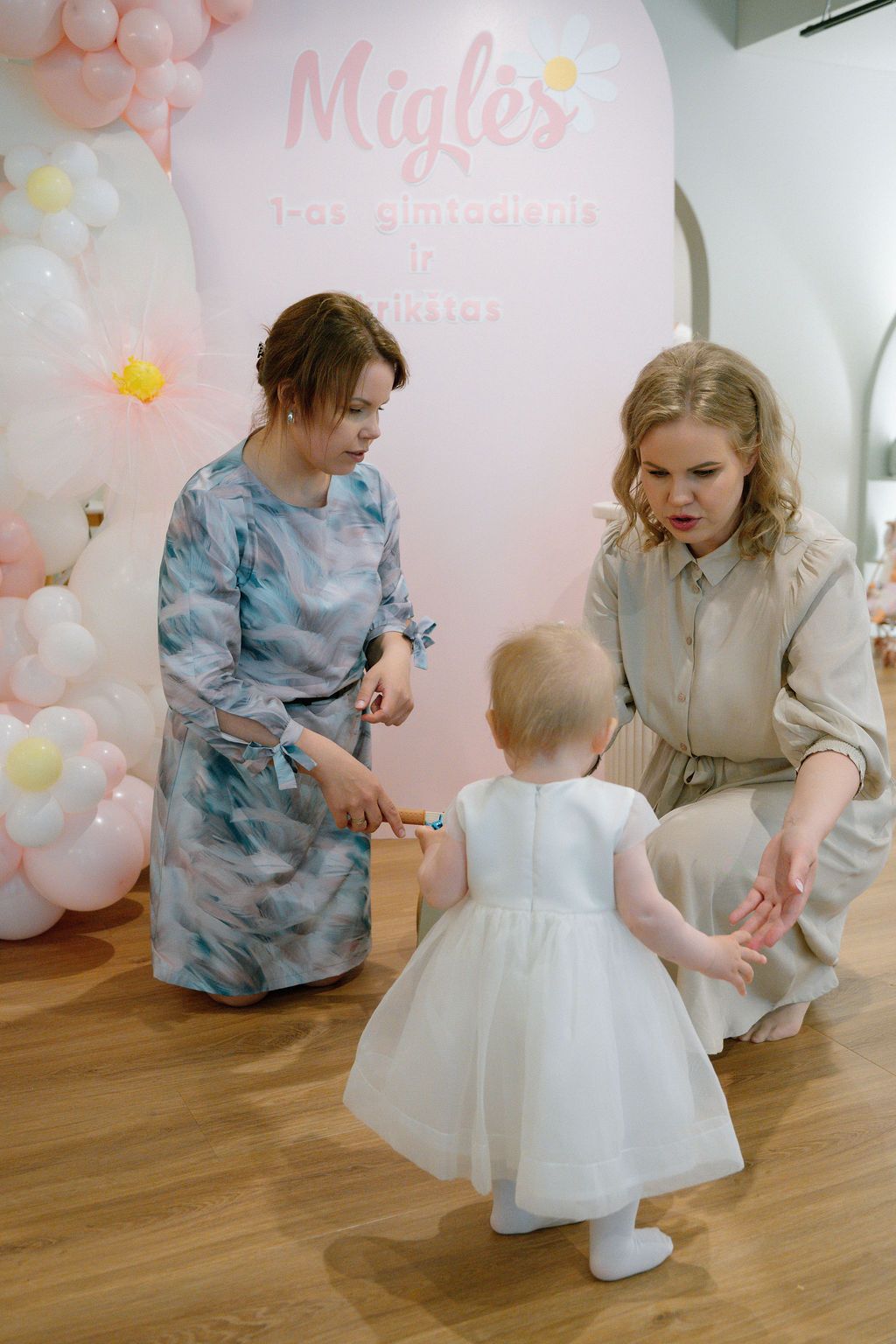 Two women celebrating a baby girl's first birthday party with pink balloon decorations at Migle's 1st birthday.