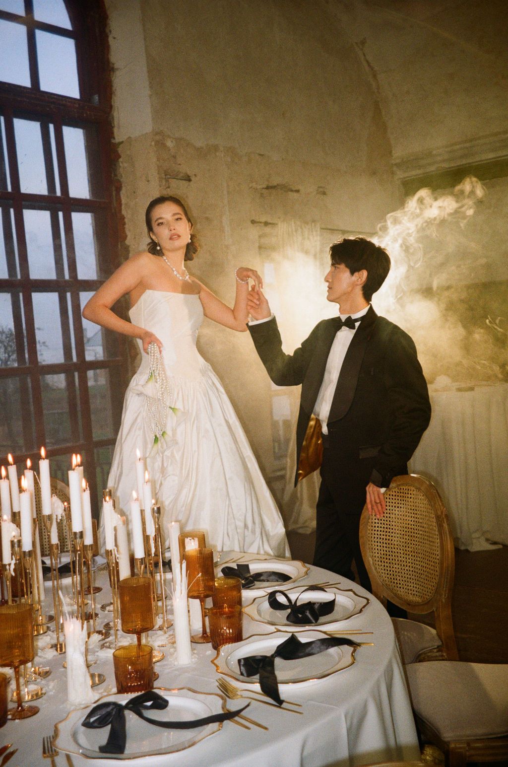 Bride and groom dancing elegantly at a candlelit wedding table in a rustic stone venue.