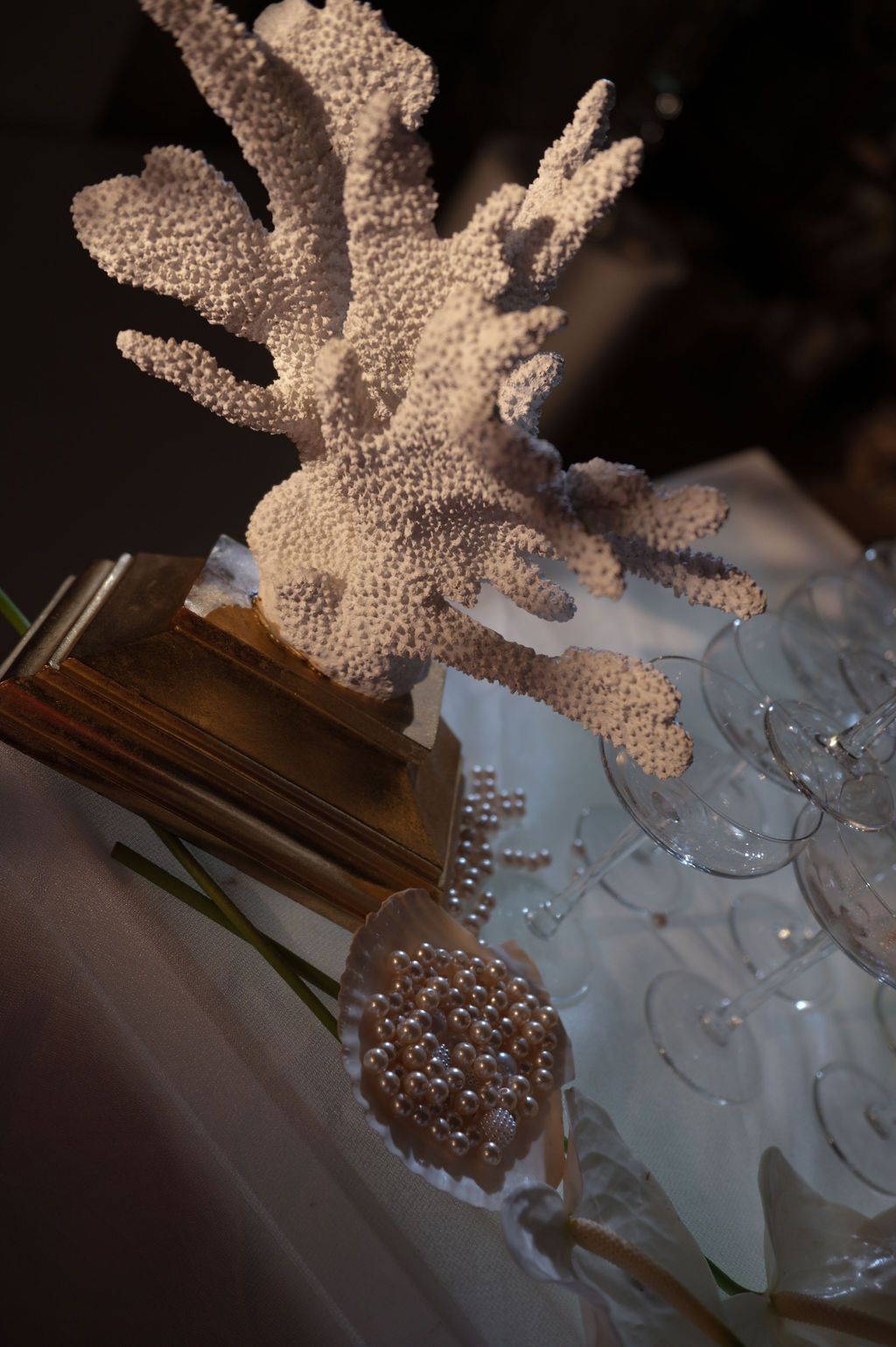 White coral centerpiece display with pearl accents and clear glassware on a decorated table.