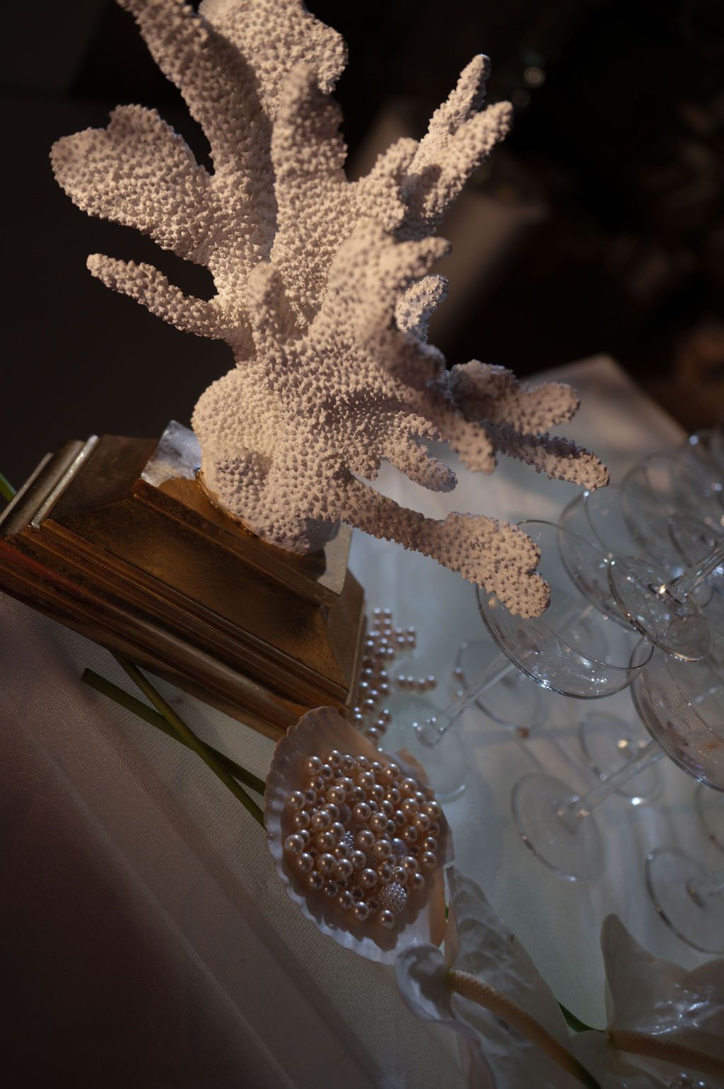 White coral reef decoration displayed on a table with pearl accents and glass stemware at an elegant event.
