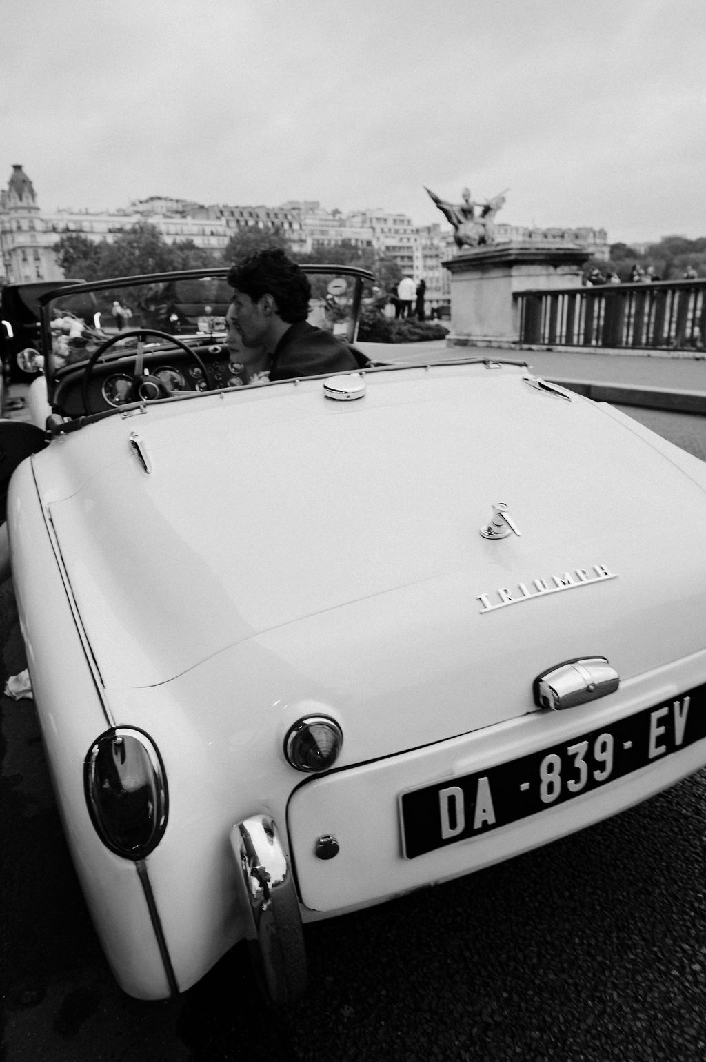 Vintage white convertible car with license plate DA-839-EV driven by a man in Paris, black and white photo.
