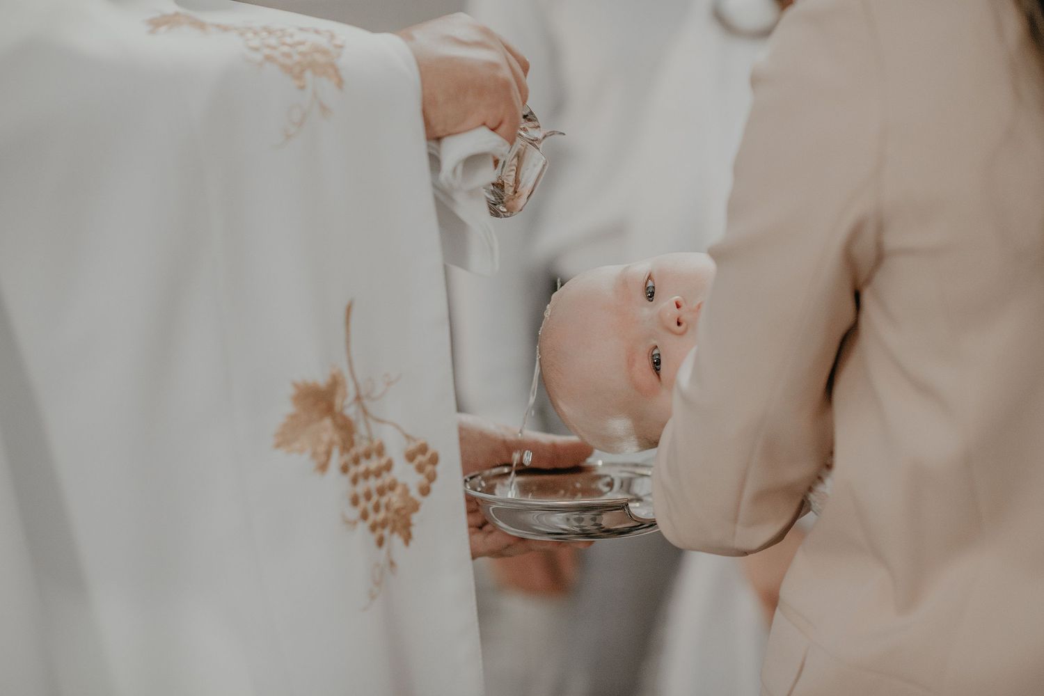 A bride and groom hold hands during an intimate wedding ceremony with soft beige and white tones.