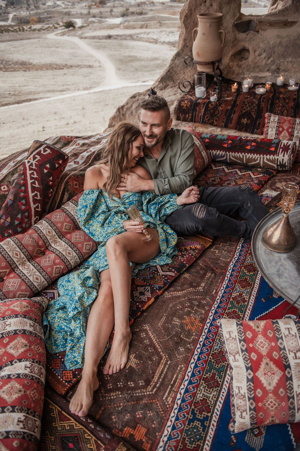 Romantic couple relaxing on vibrant Turkish kilim rugs and cushions in a cave setting in Cappadocia, Turkey.