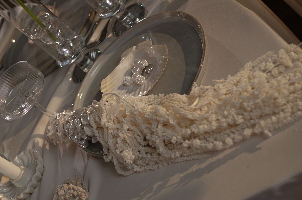 Elegant white table setting with decorative pearl garland and crystal glassware for a formal occasion.