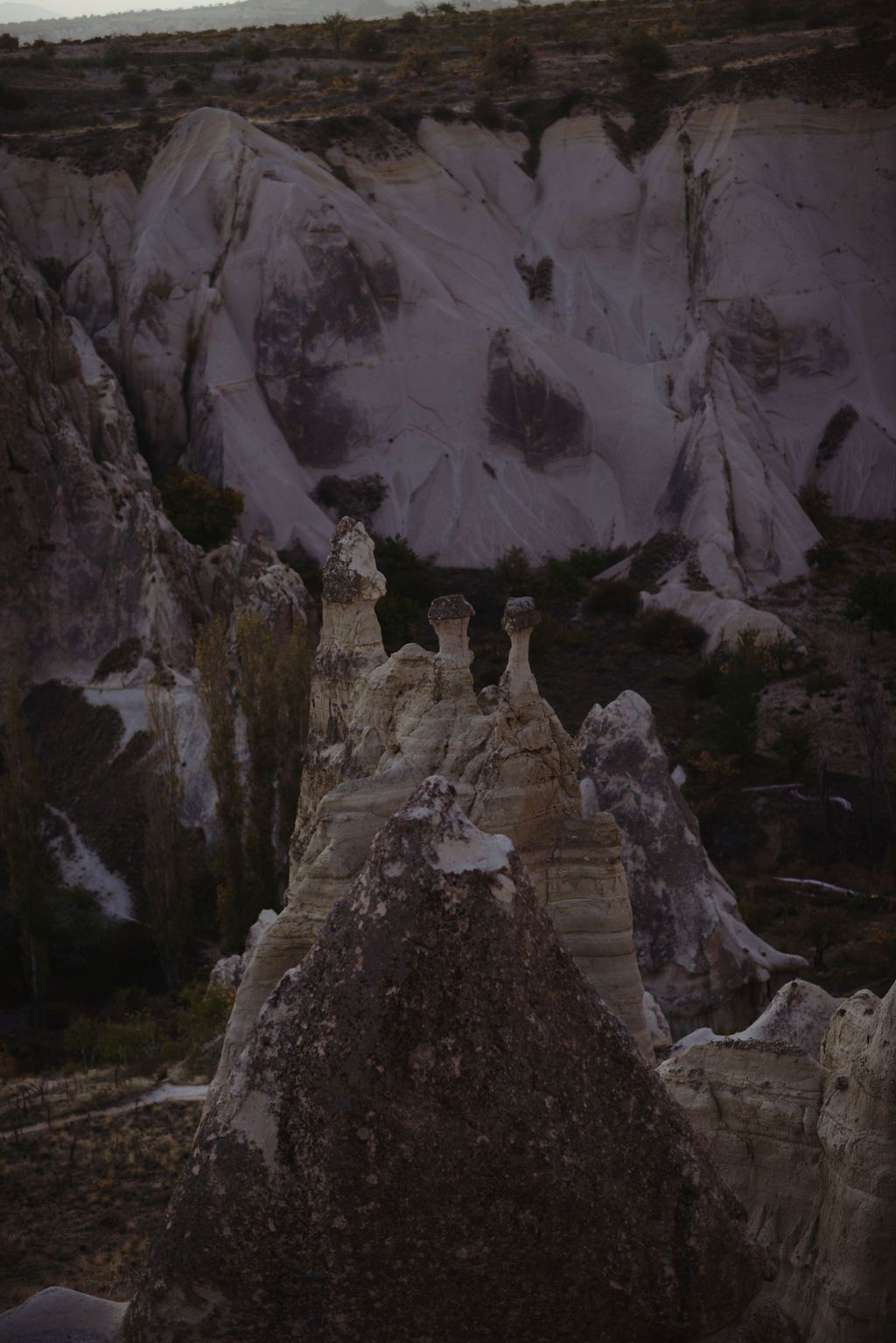 Dramatic fairy chimney rock formations in Cappadocia, Turkey, with white volcanic tuff landscape in dim light.