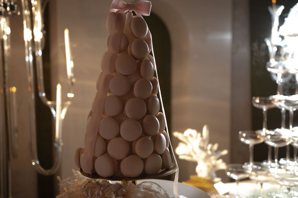 Elegant macaron tower dessert display with pink ribbon topper at a wedding or special event reception.