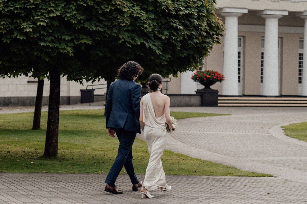 Bride and groom walking hand in hand through elegant garden venue on their wedding day.