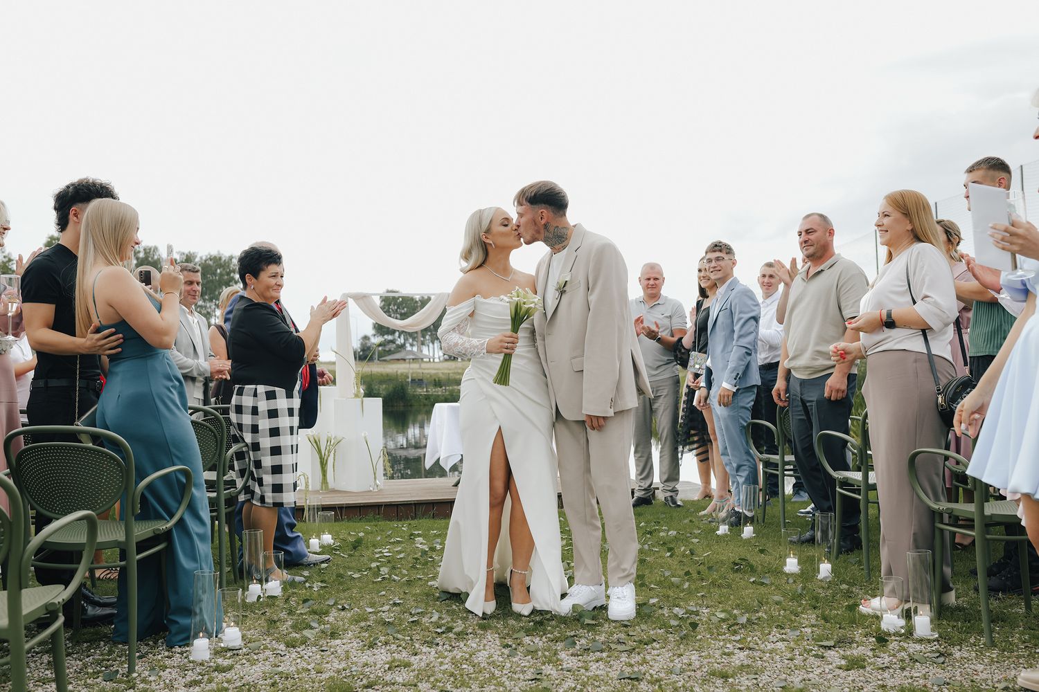A panoramic view of wedding guests dressed in white and cream colors mingling outdoors during a celebration.