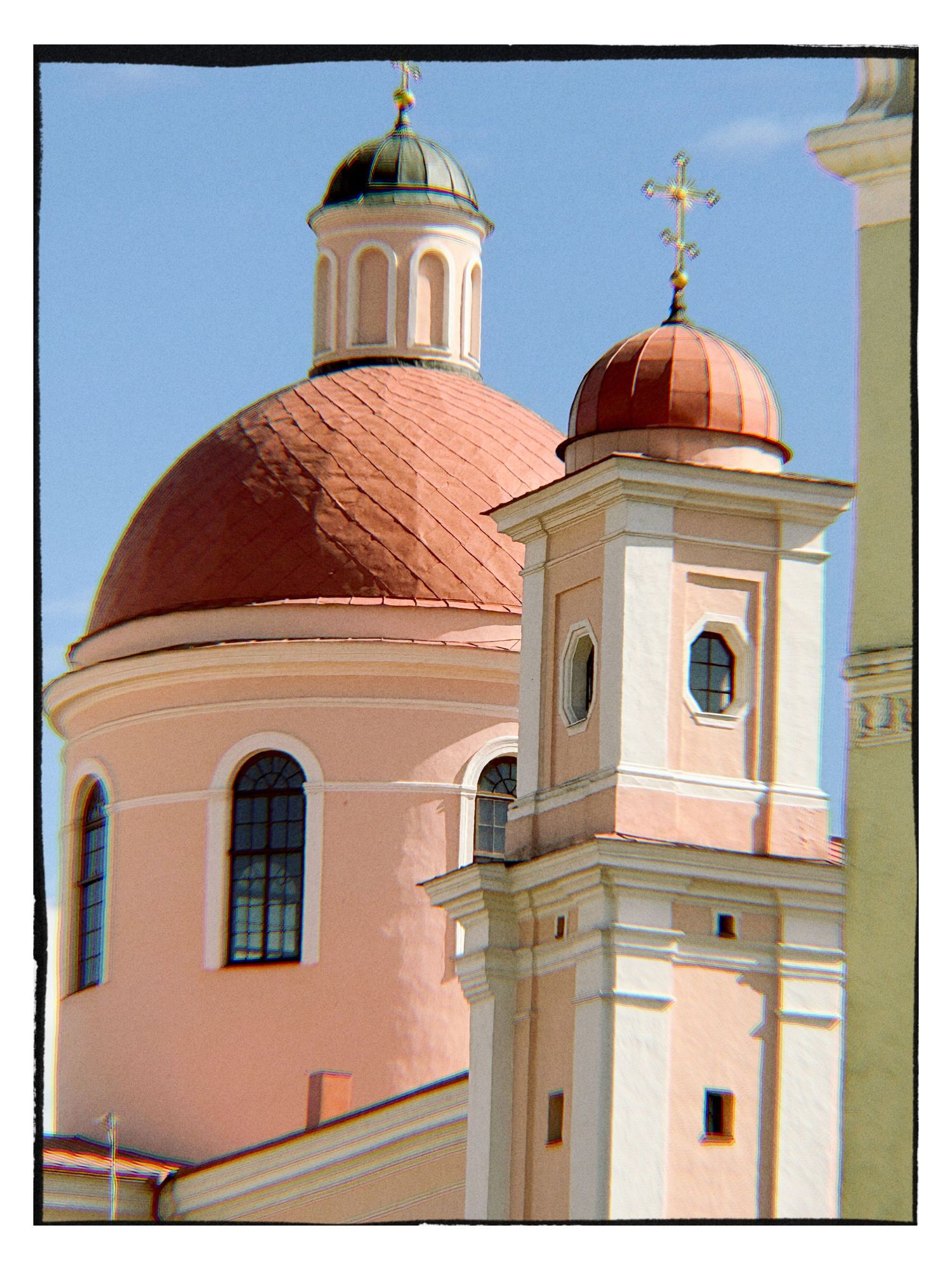 Pink baroque church with terracotta domes and golden crosses against a blue sky.