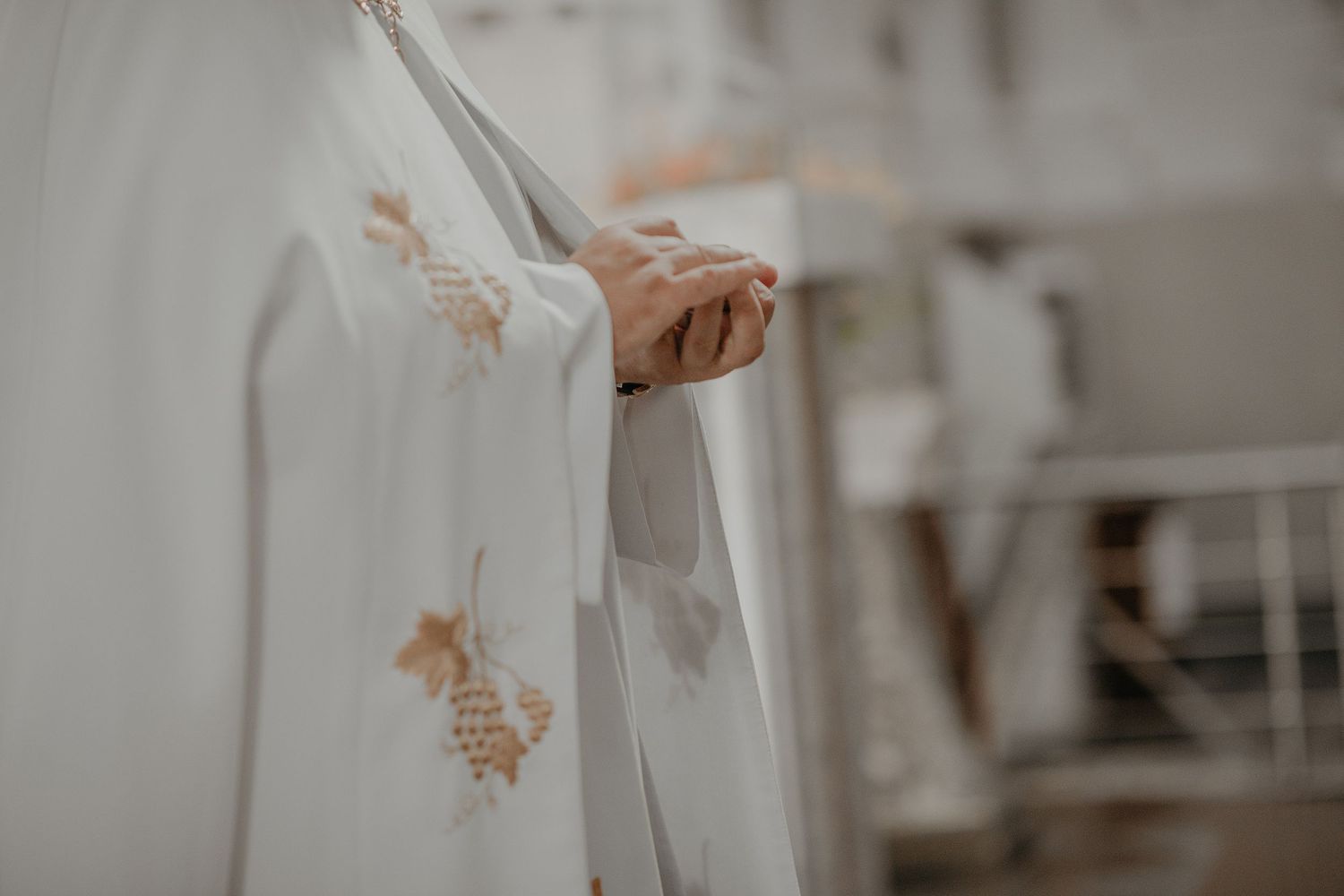 A person wearing a white lace dress holds a bouquet while walking down a rustic wooden staircase.
