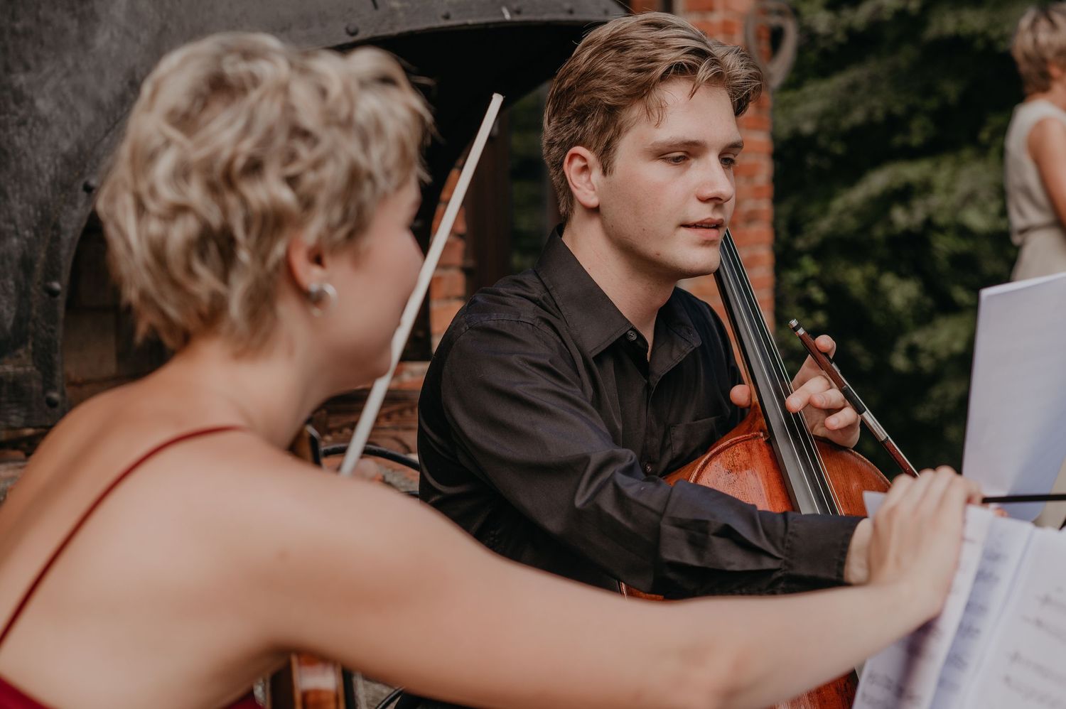 Musicians performing at an outdoor wedding ceremony with string instruments.