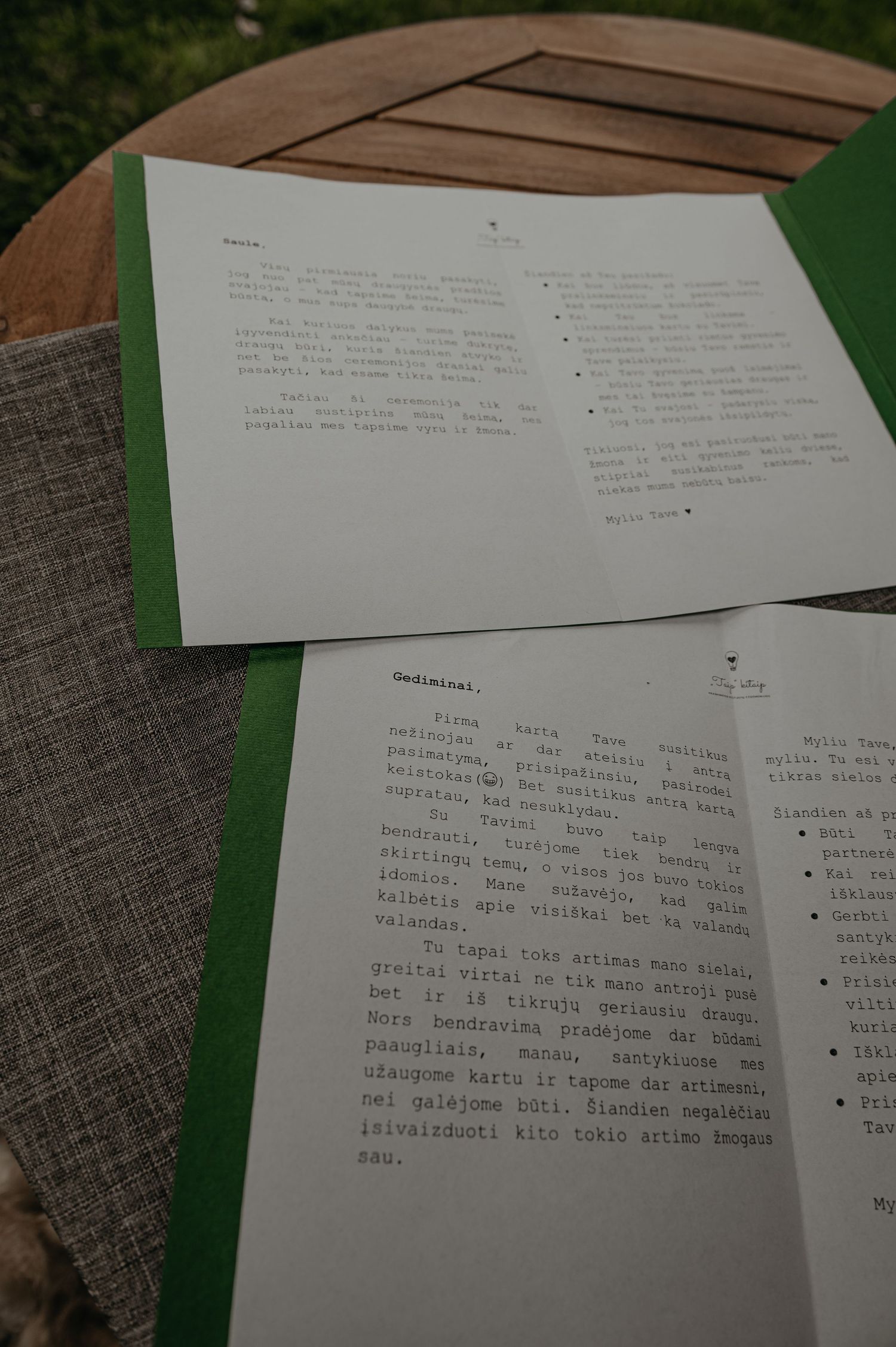 Multiple pages of typed or printed text documents laid out on a green surface in natural lighting.