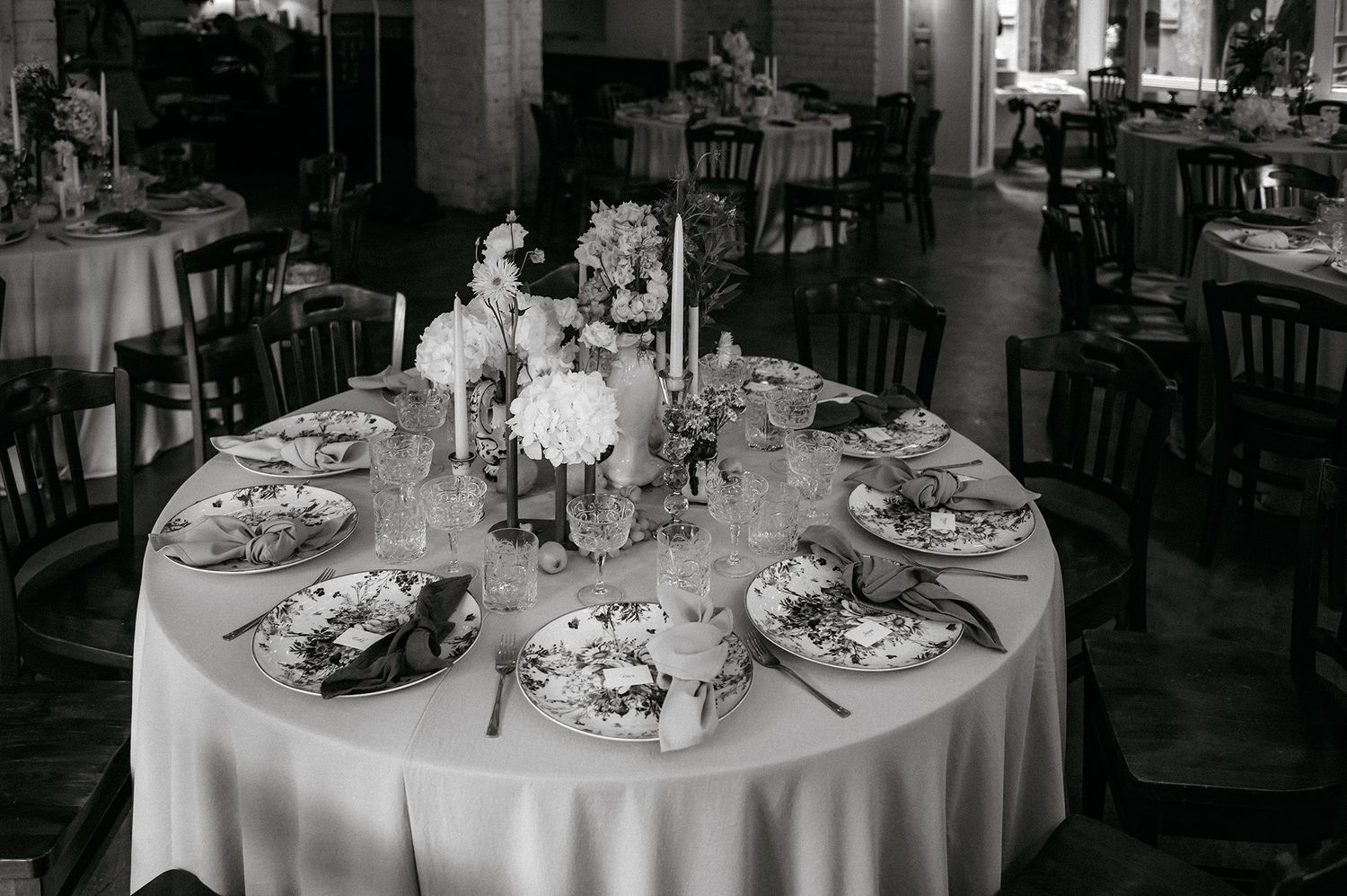 Black and white photographs of elegant round dining tables set for a formal event with white linens and centerpieces.