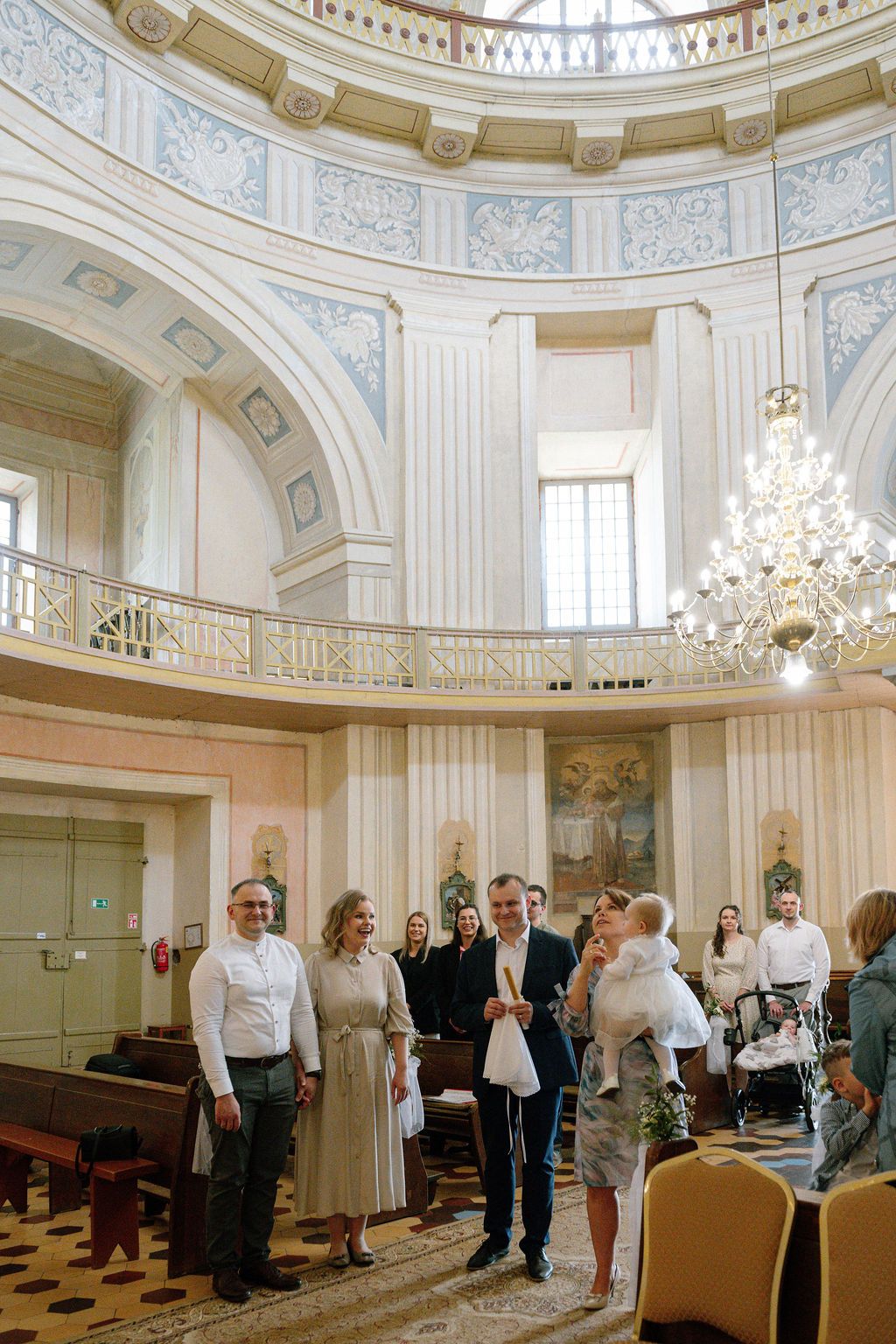 Elegant neoclassical church interior with chandelier and guests gathered for a ceremony.