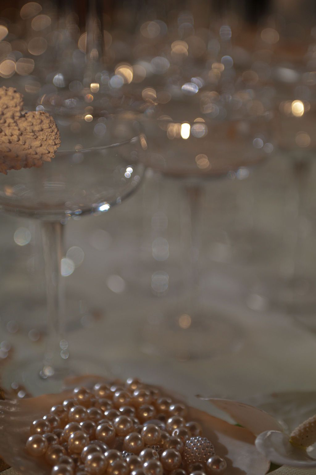 Elegant champagne glasses with pearl jewelry and bokeh lights at a glamorous event table setting.