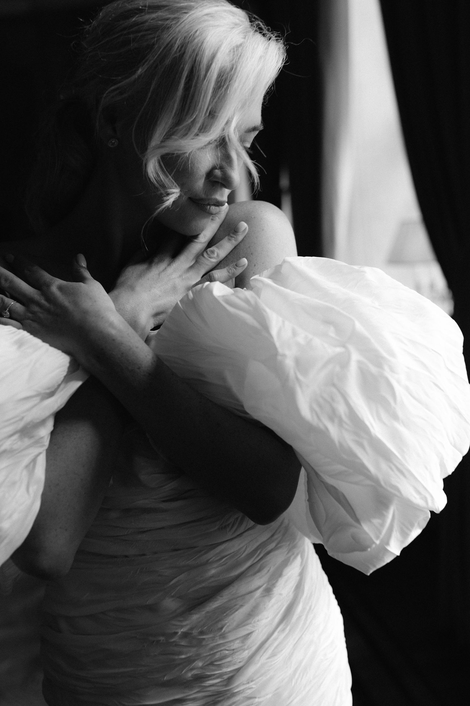 Black and white artistic photo series showing a figure in flowing white fabric creating graceful movement against dark background.